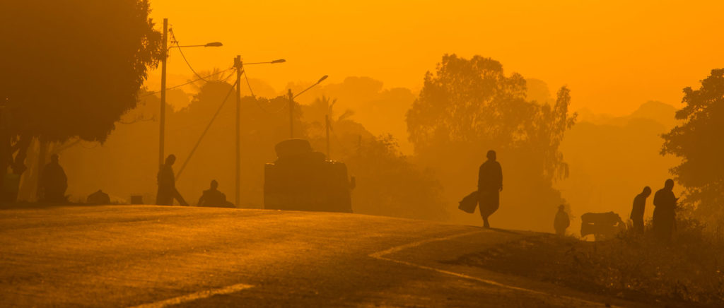 Silhouettes of commuters along a road at sunrise in Mozambique