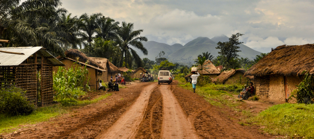 Person walking down a dirt road through a village in Democratic Republic of the Congo